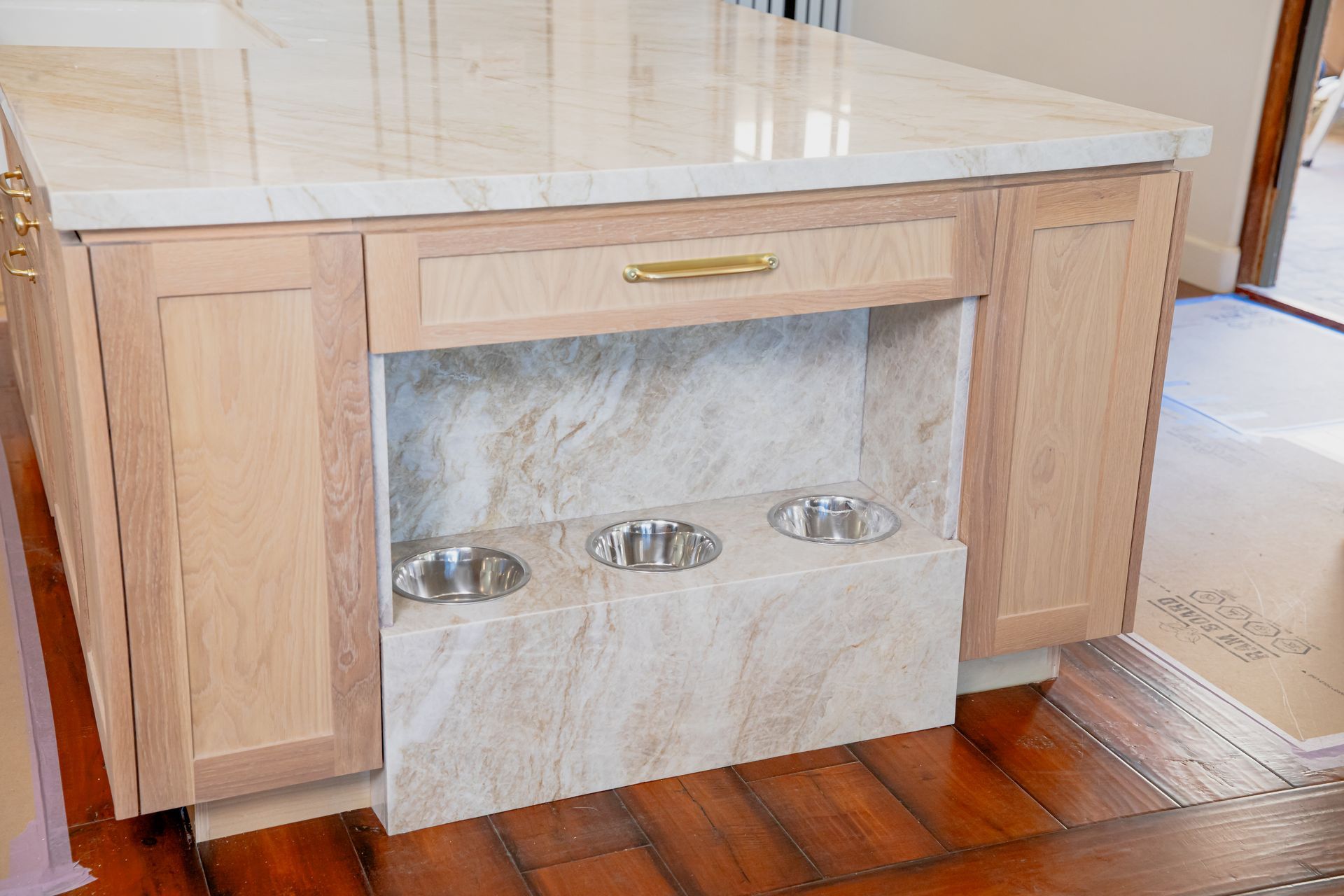 A kitchen island with two dog bowls underneath it.