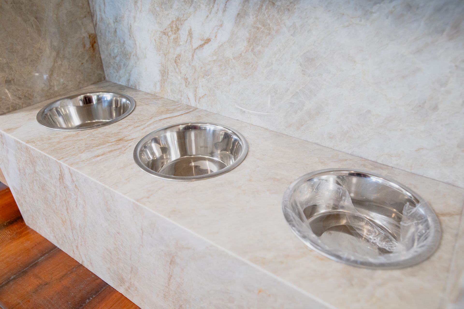 Three stainless steel bowls are sitting on top of a marble counter.
