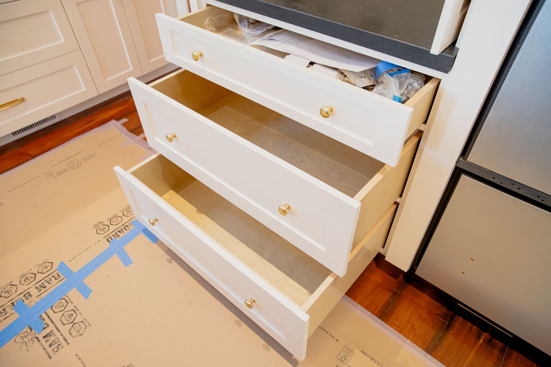 A dresser with three drawers open in a kitchen