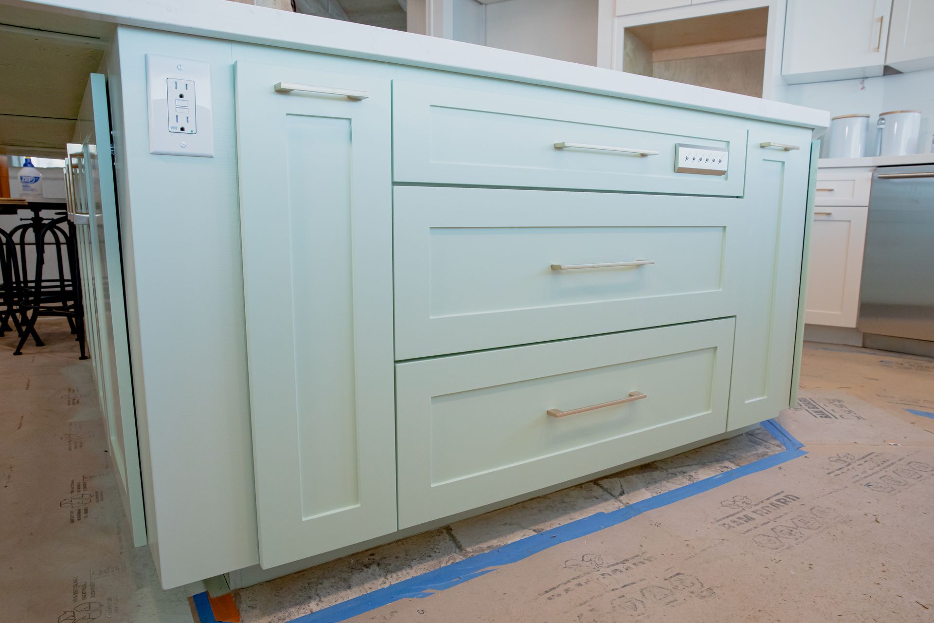 A kitchen island with white cabinets and drawers is being built.