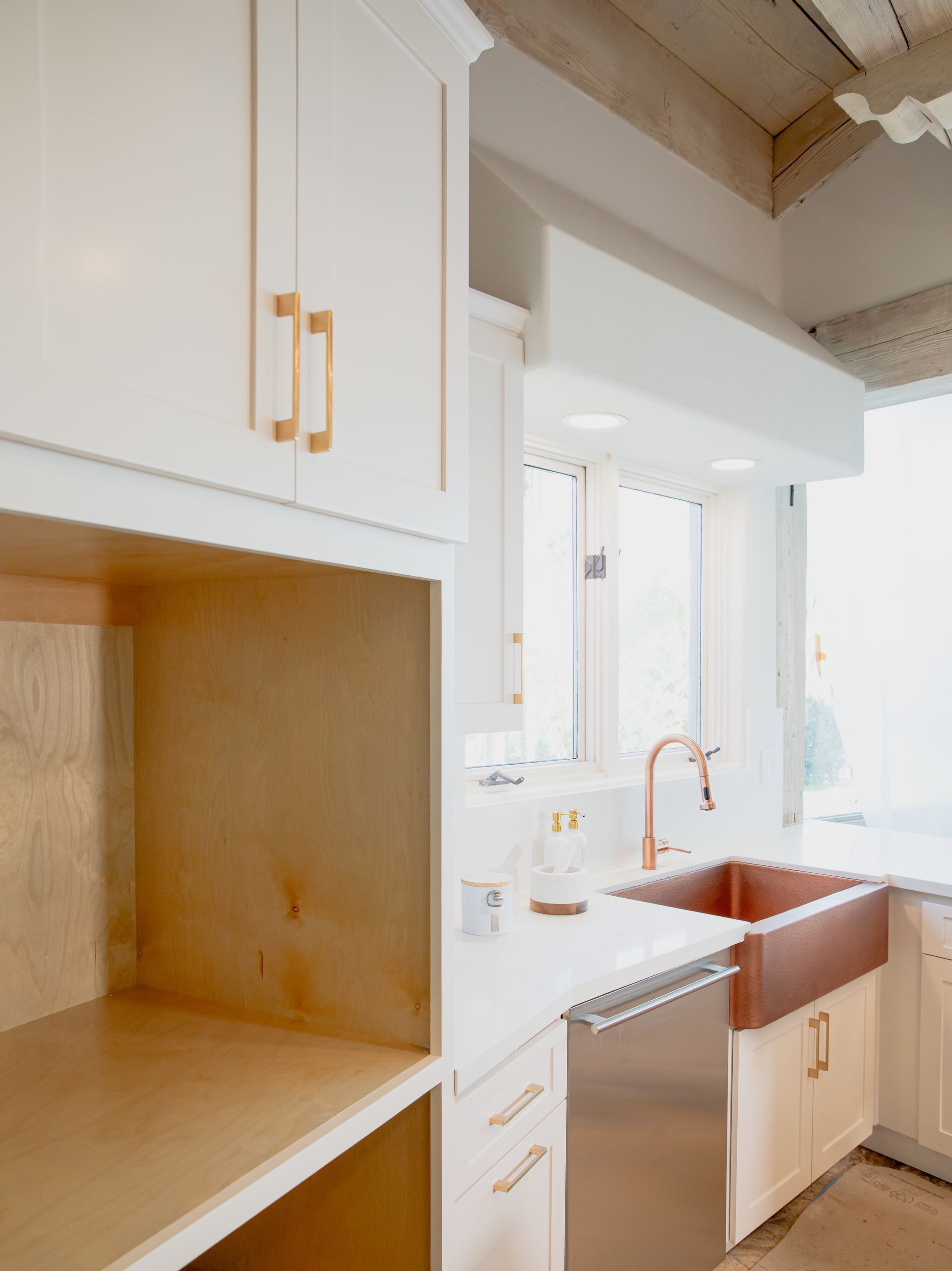 A kitchen with white cabinets and a copper sink