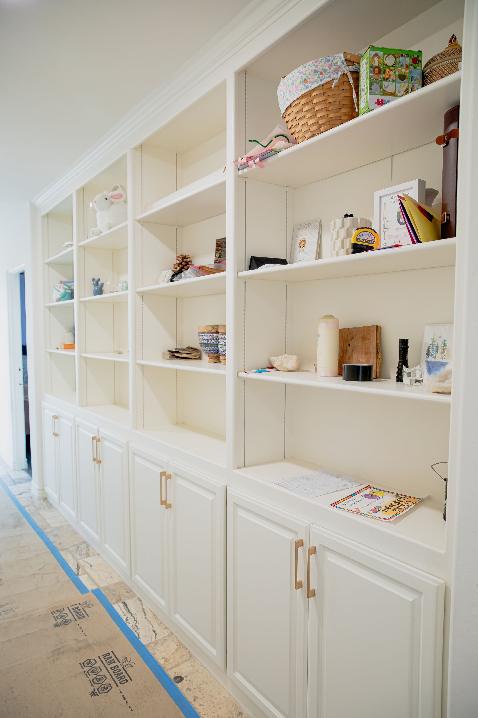 A row of white shelves filled with lots of items in a room.