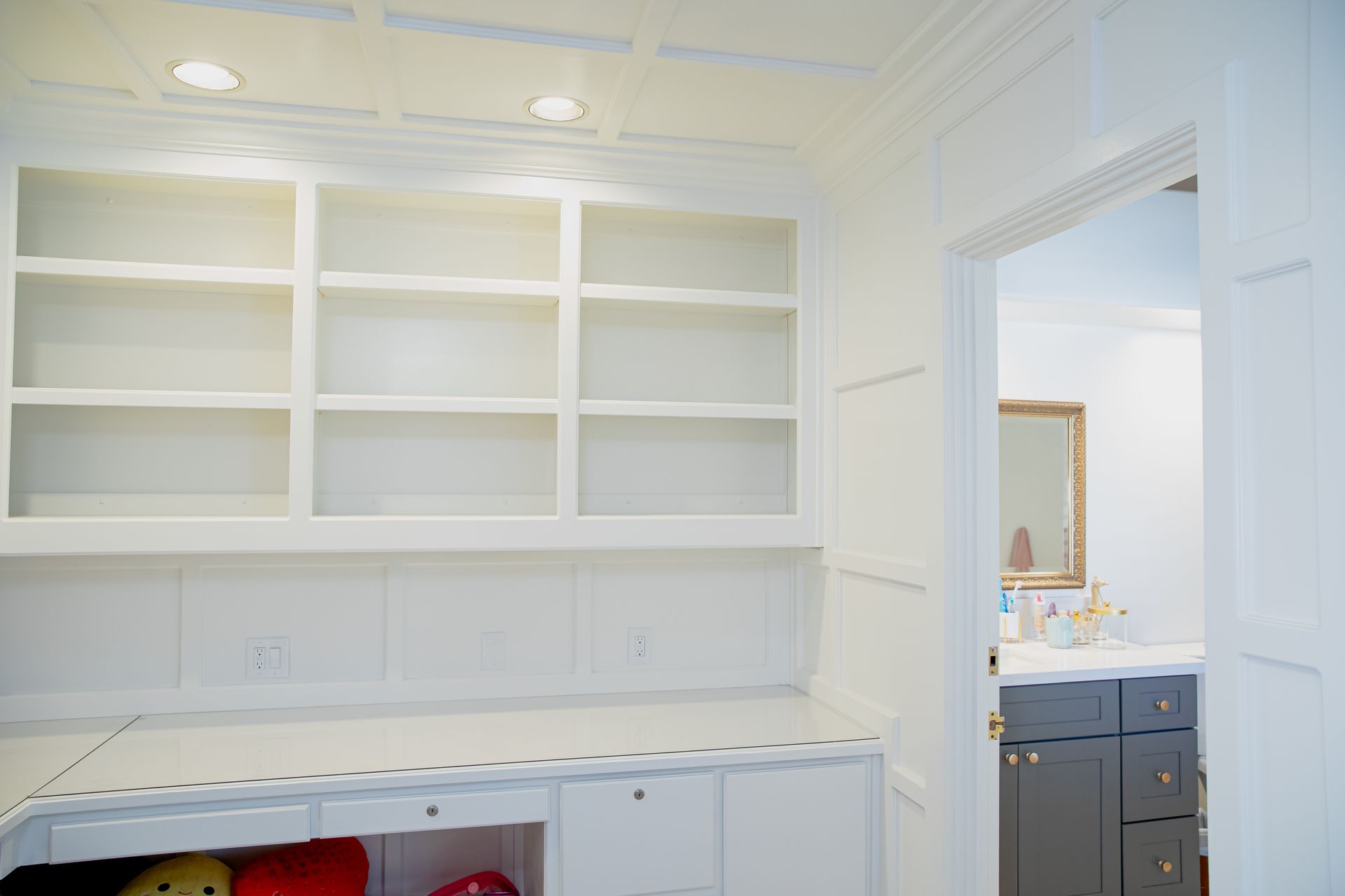 A room with a lot of shelves and a door leading to a bathroom.
