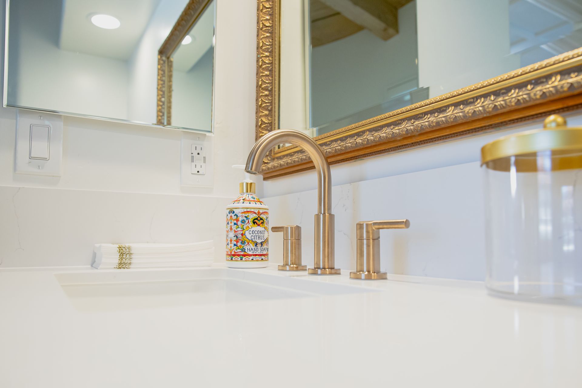 A bathroom sink with a gold faucet and a mirror.