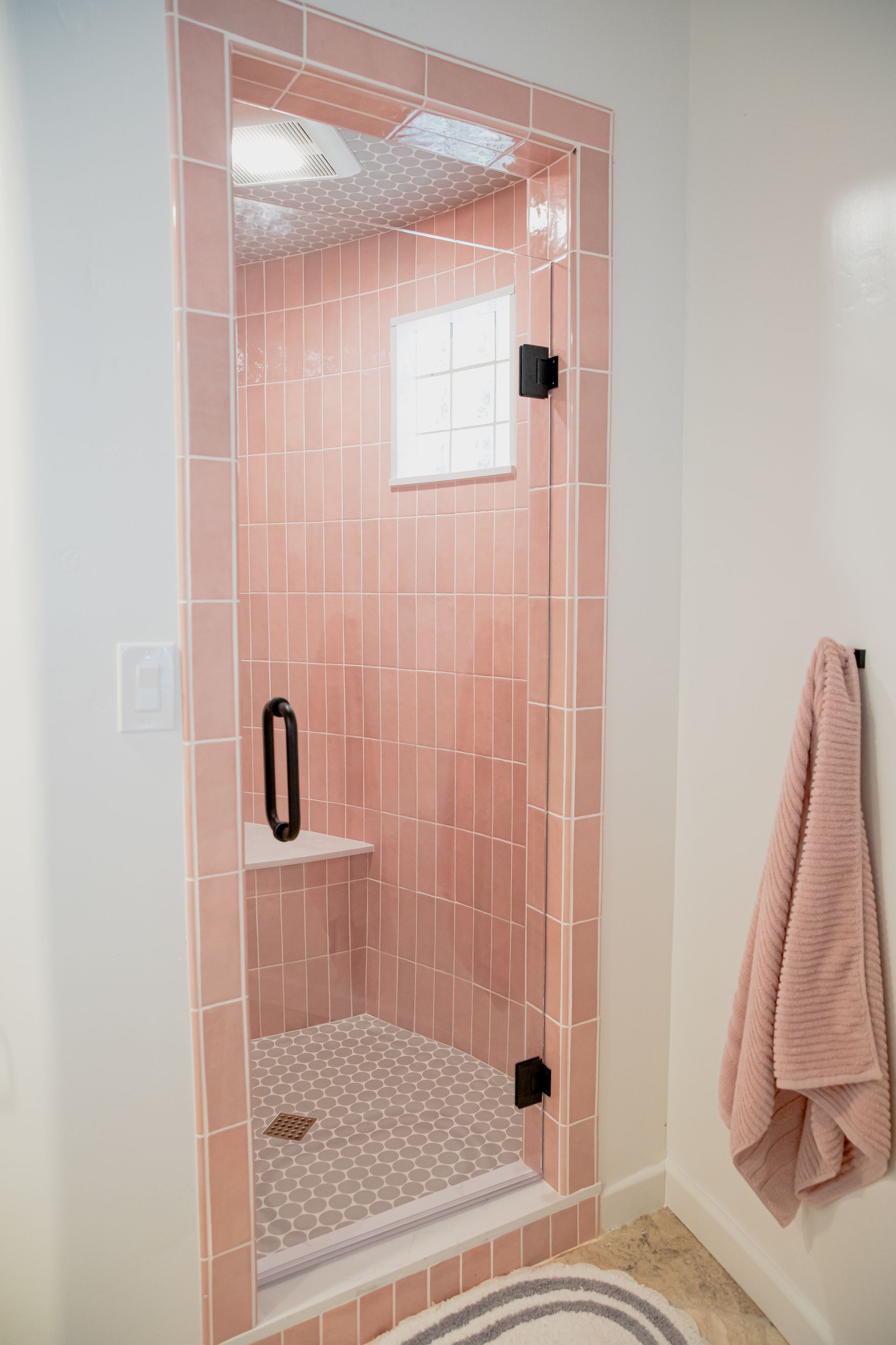 A bathroom with pink tiles and a glass shower door.