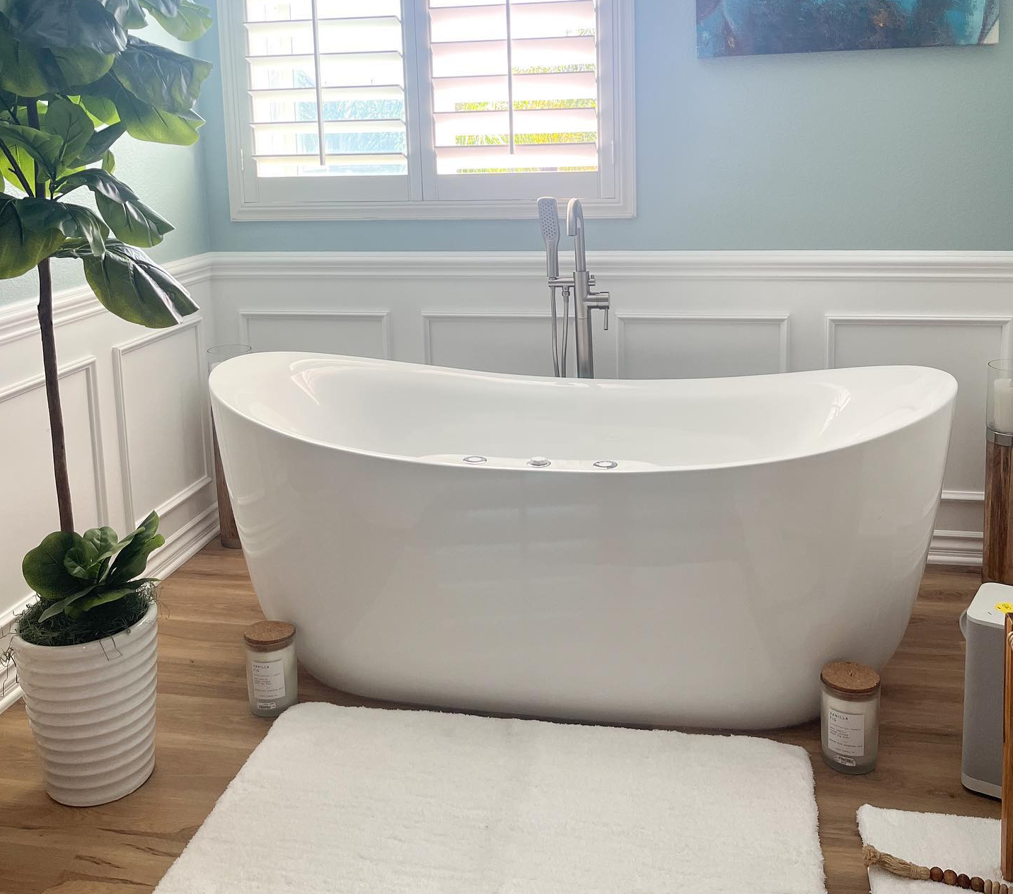 A bathroom with a large white bathtub and a plant.