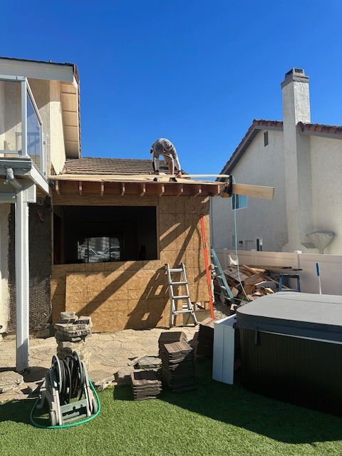 A man is working on the roof of a house next to a hot tub.