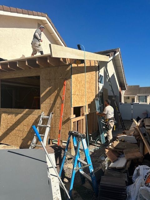 A man is standing on the roof of a house.