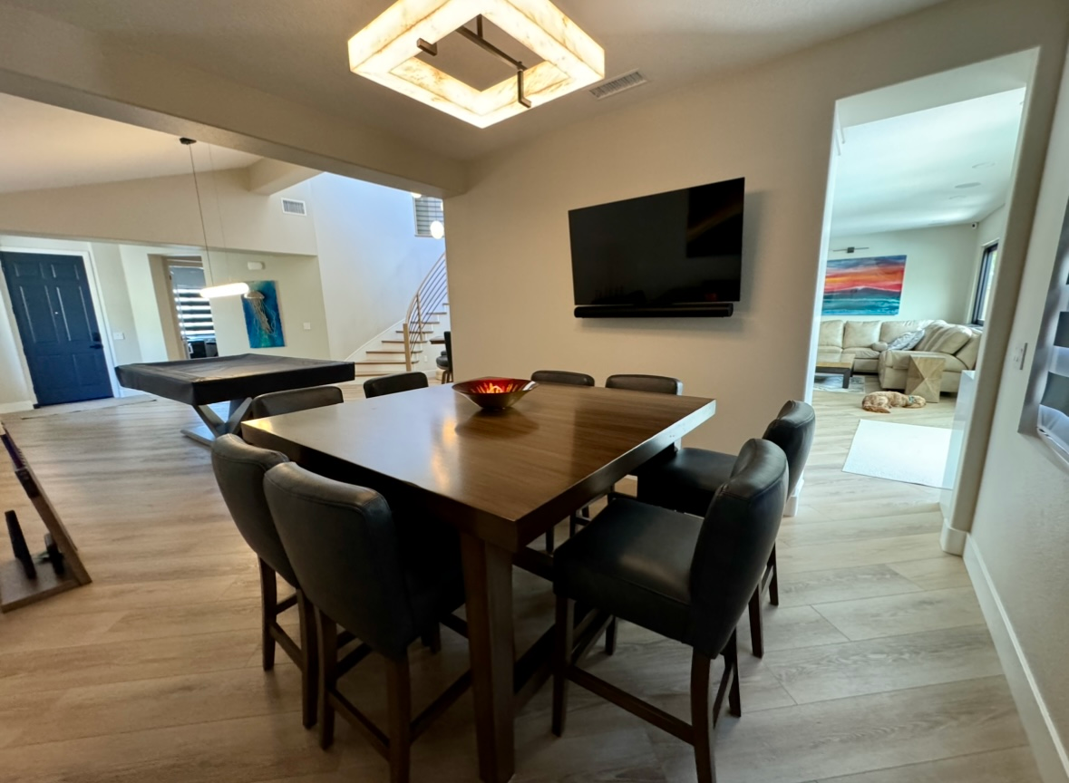 A dining room with a table and chairs and a pool table.