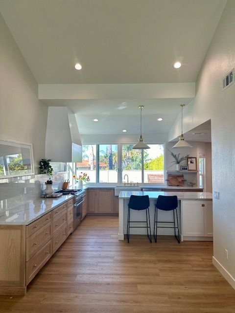 A kitchen with wooden floors and white cabinets and stools