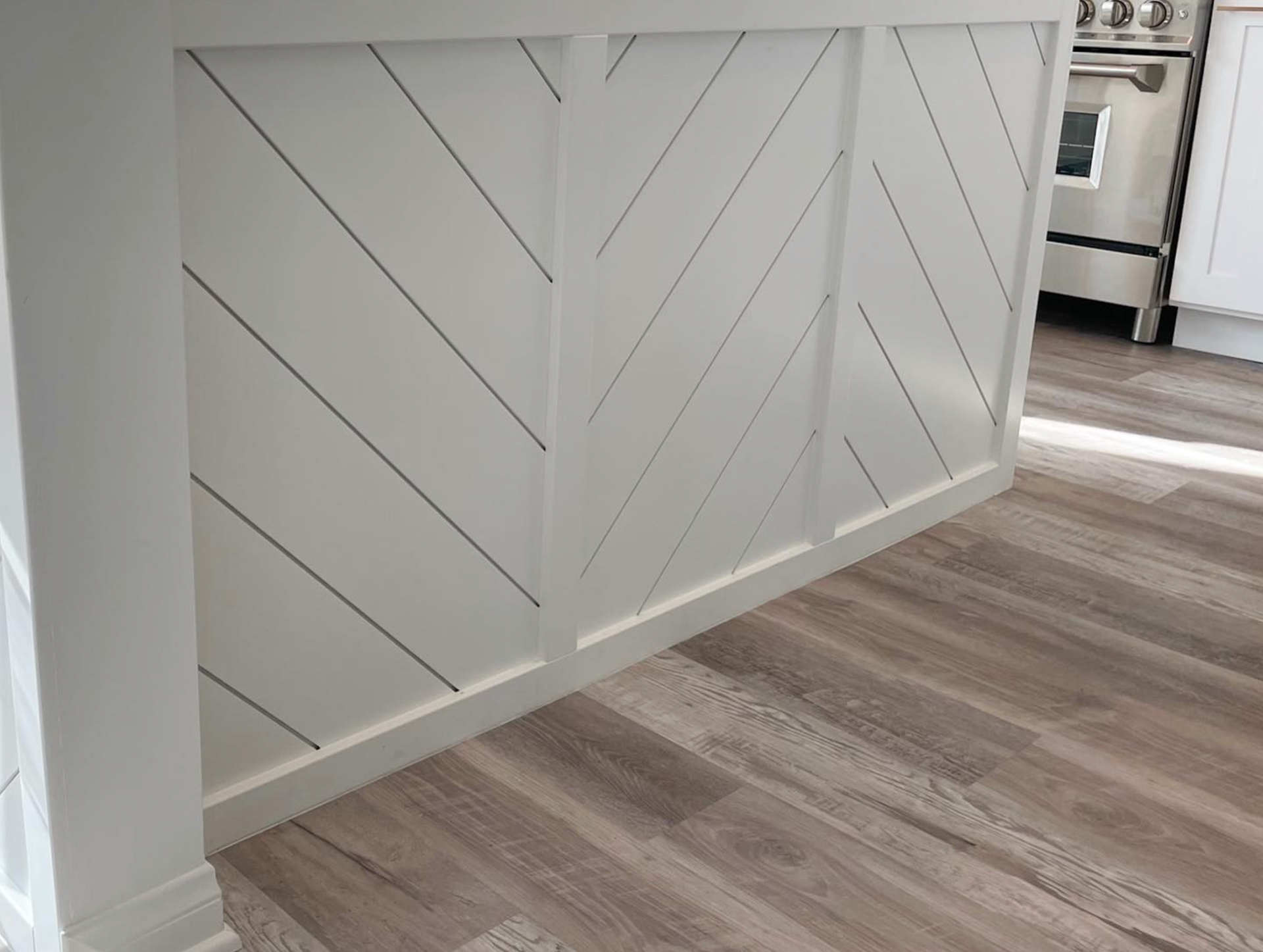 A kitchen with a wooden floor , white cabinets , and a stove.