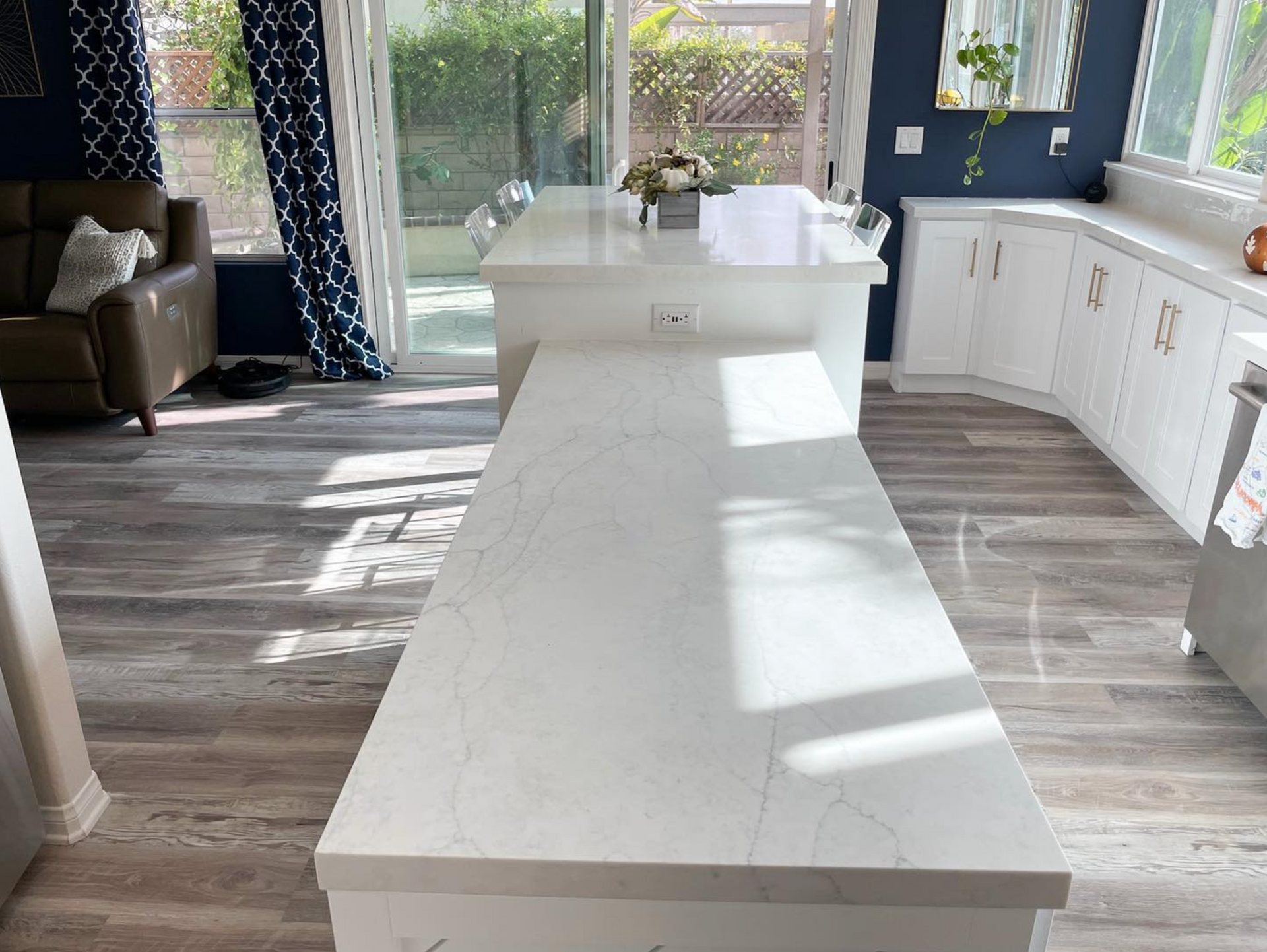 A kitchen with a large island and a couch in the background.