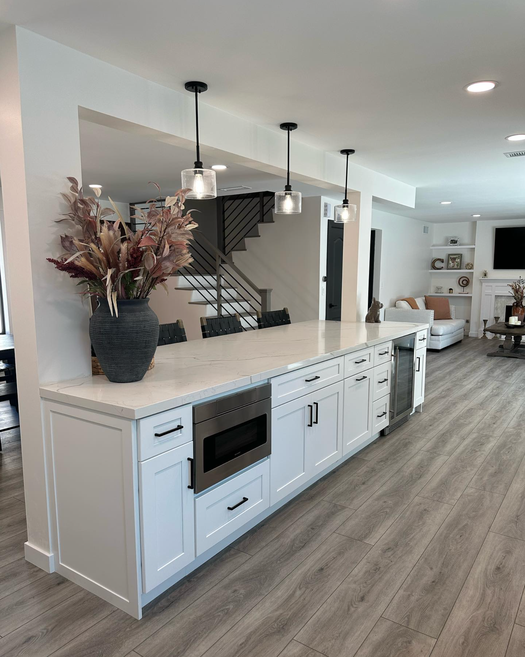A kitchen with white cabinets and a vase of flowers on the counter.