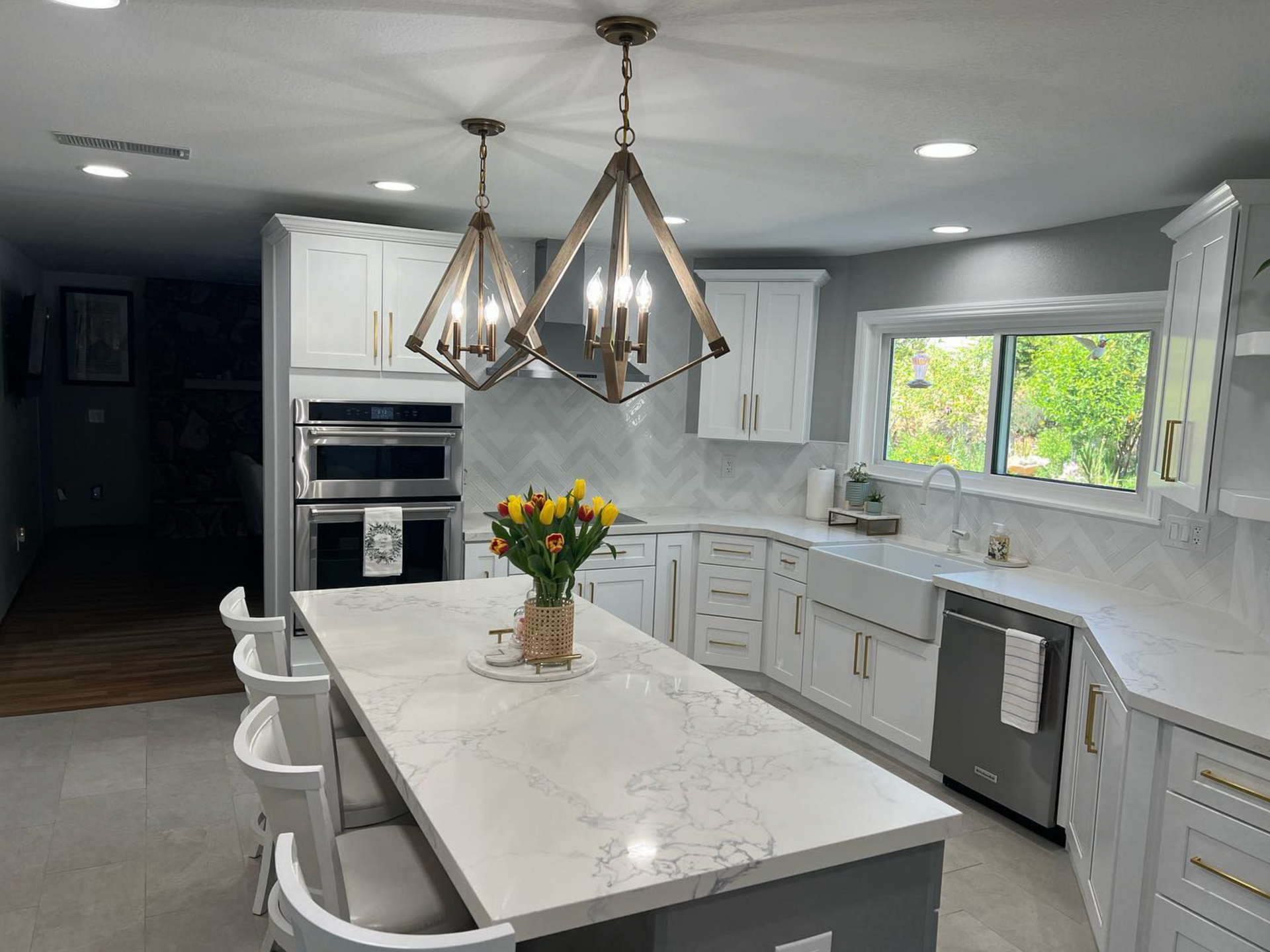 A kitchen with white cabinets and a large island with a vase of flowers on it.