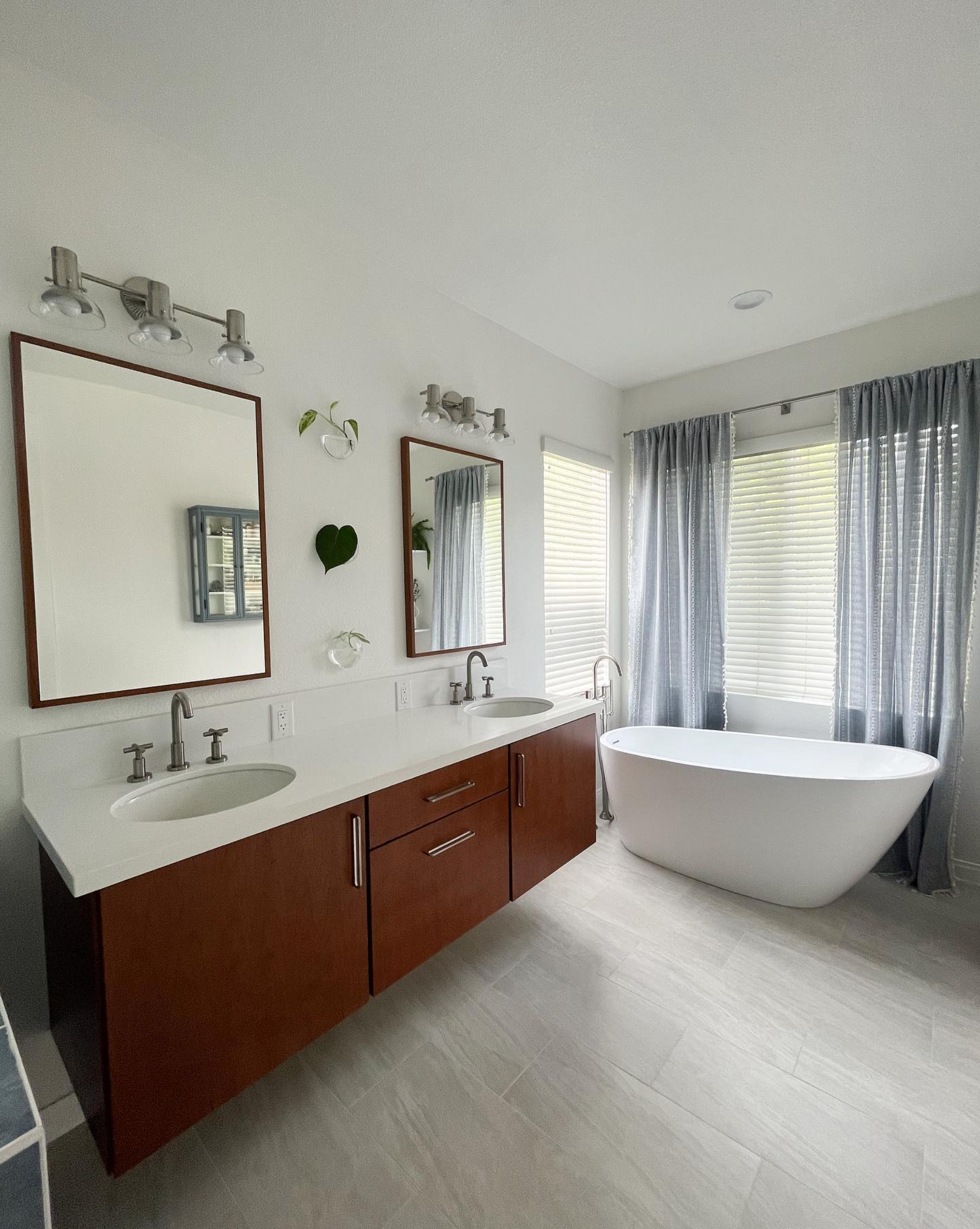 A bathroom with two sinks , two mirrors and a bathtub.