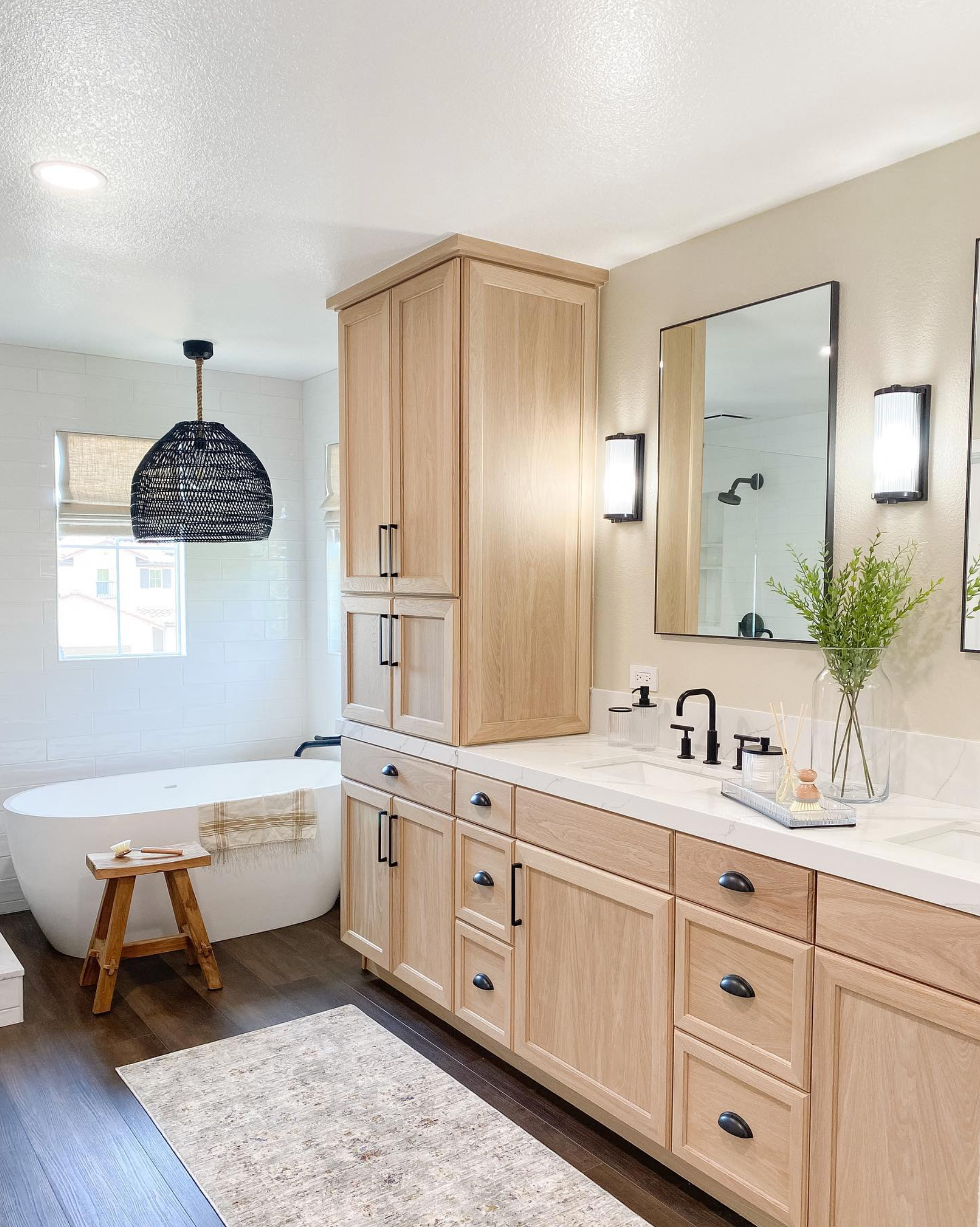 A bathroom with a tub , sink , mirror and cabinets.