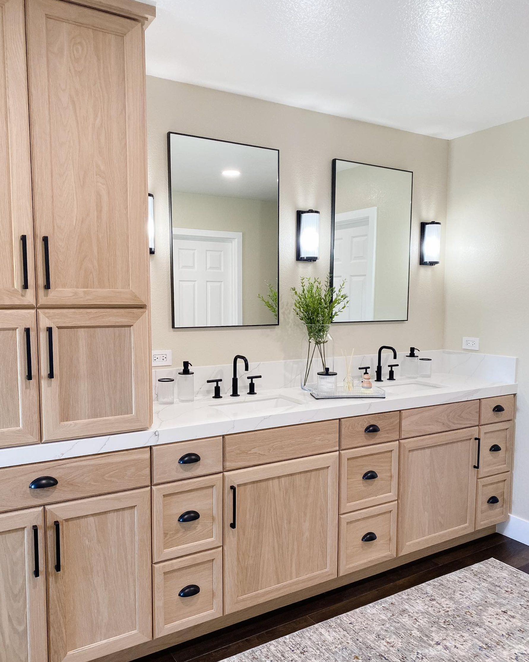 A bathroom with two sinks , two mirrors , and wooden cabinets.
