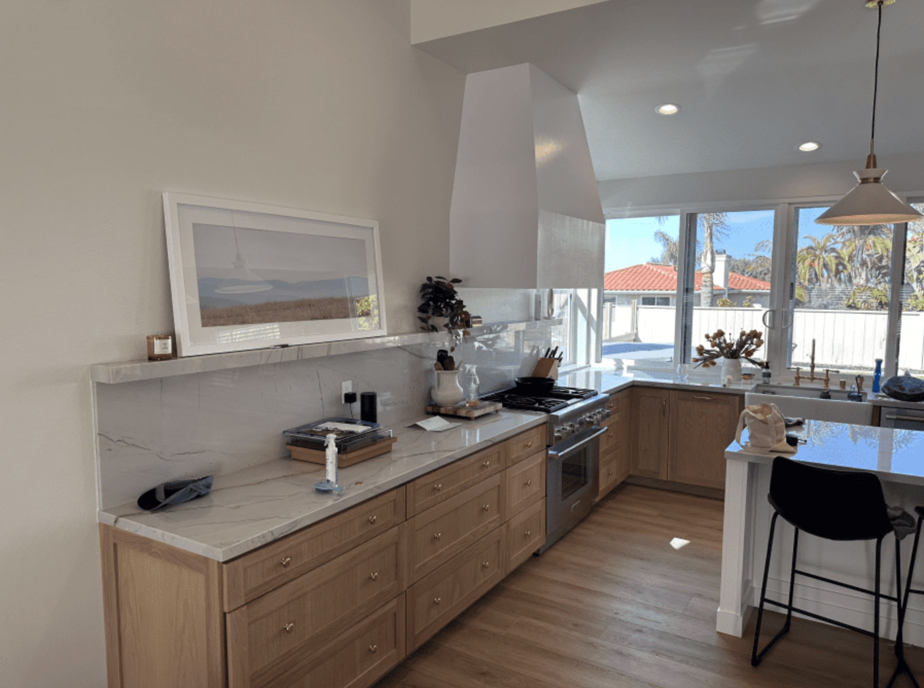 A kitchen with wooden cabinets , stainless steel appliances , and a large window.