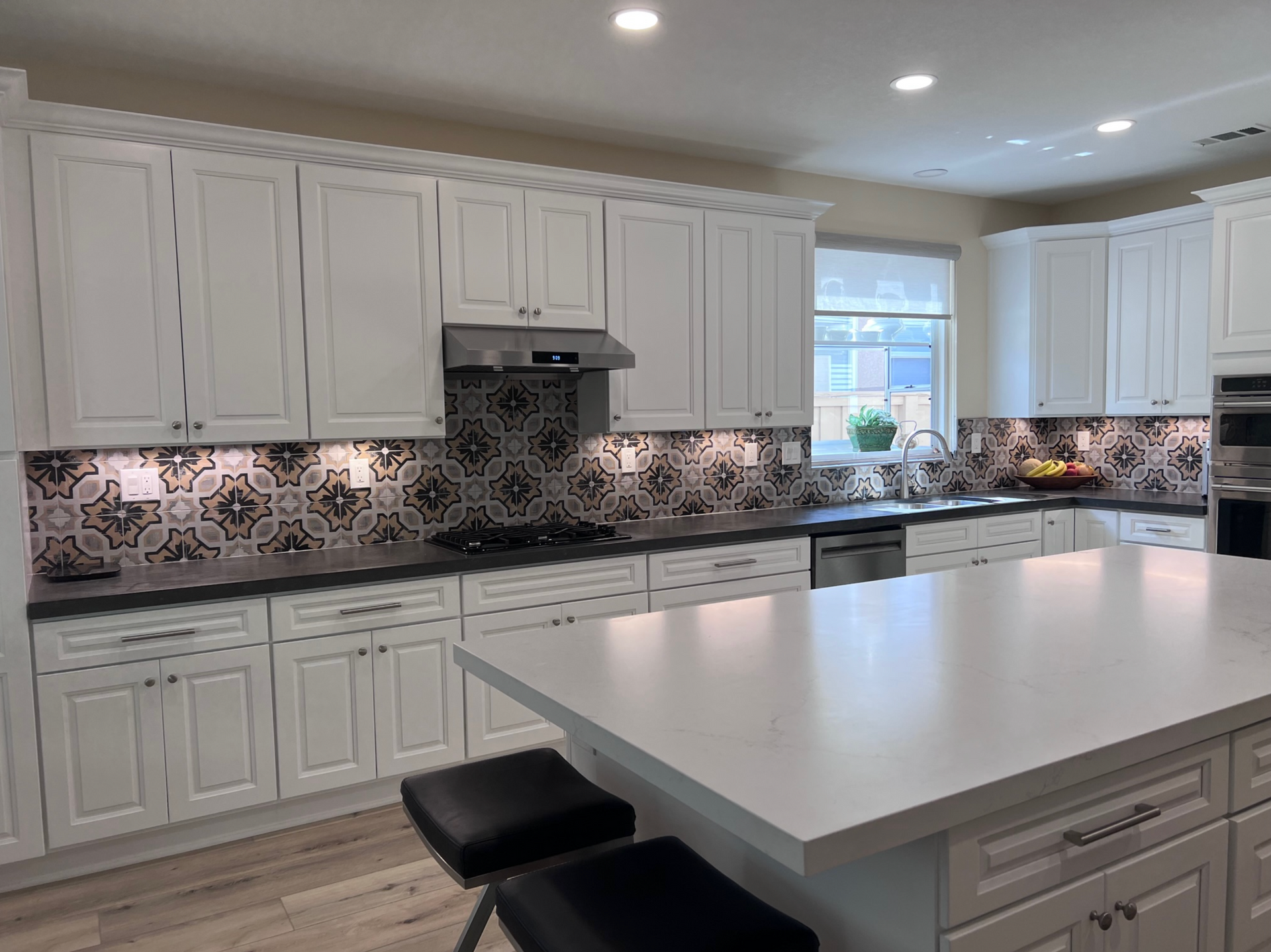 A kitchen with white cabinets and a large island in the middle.