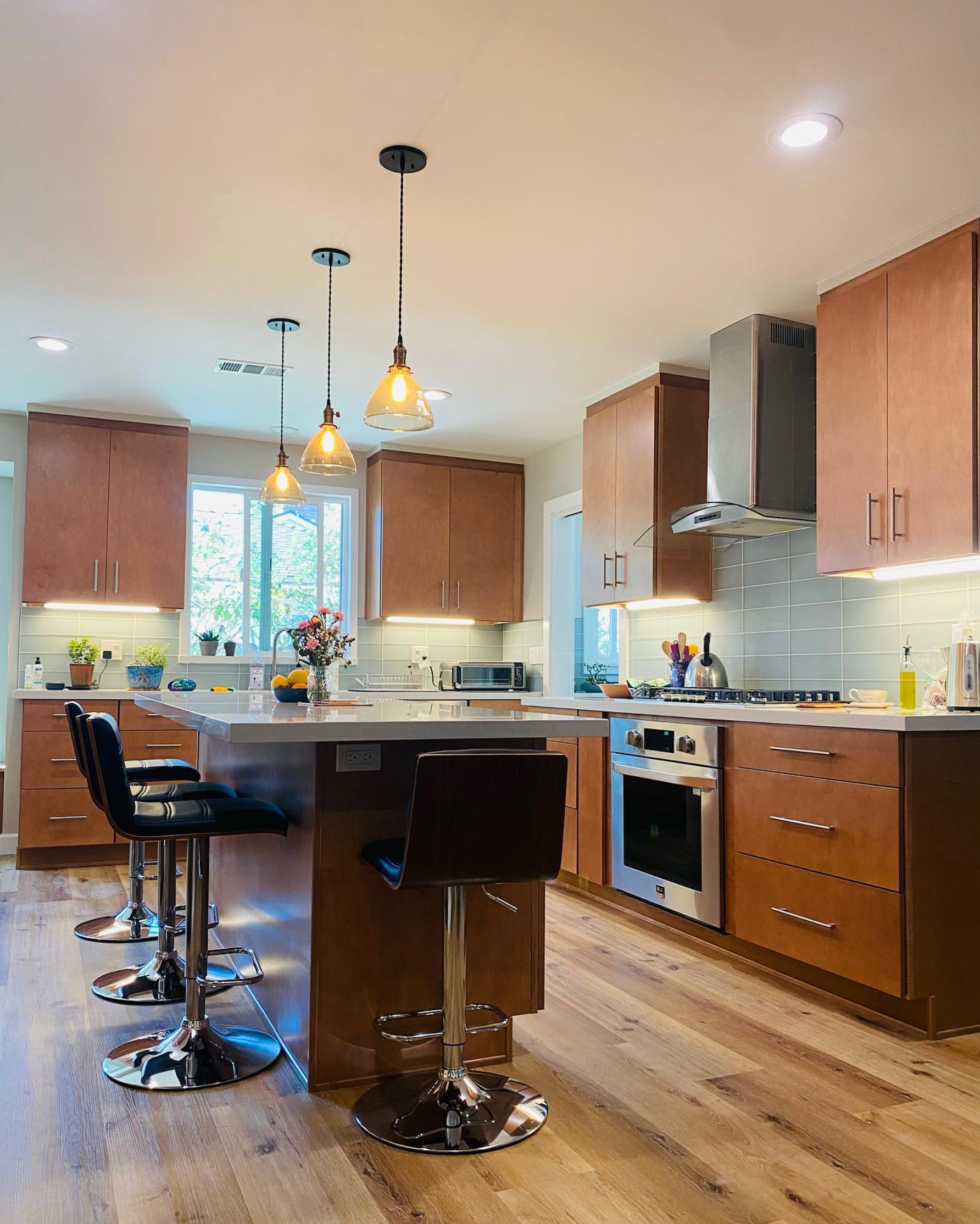 A kitchen with wooden cabinets and stools and a large island in the middle.