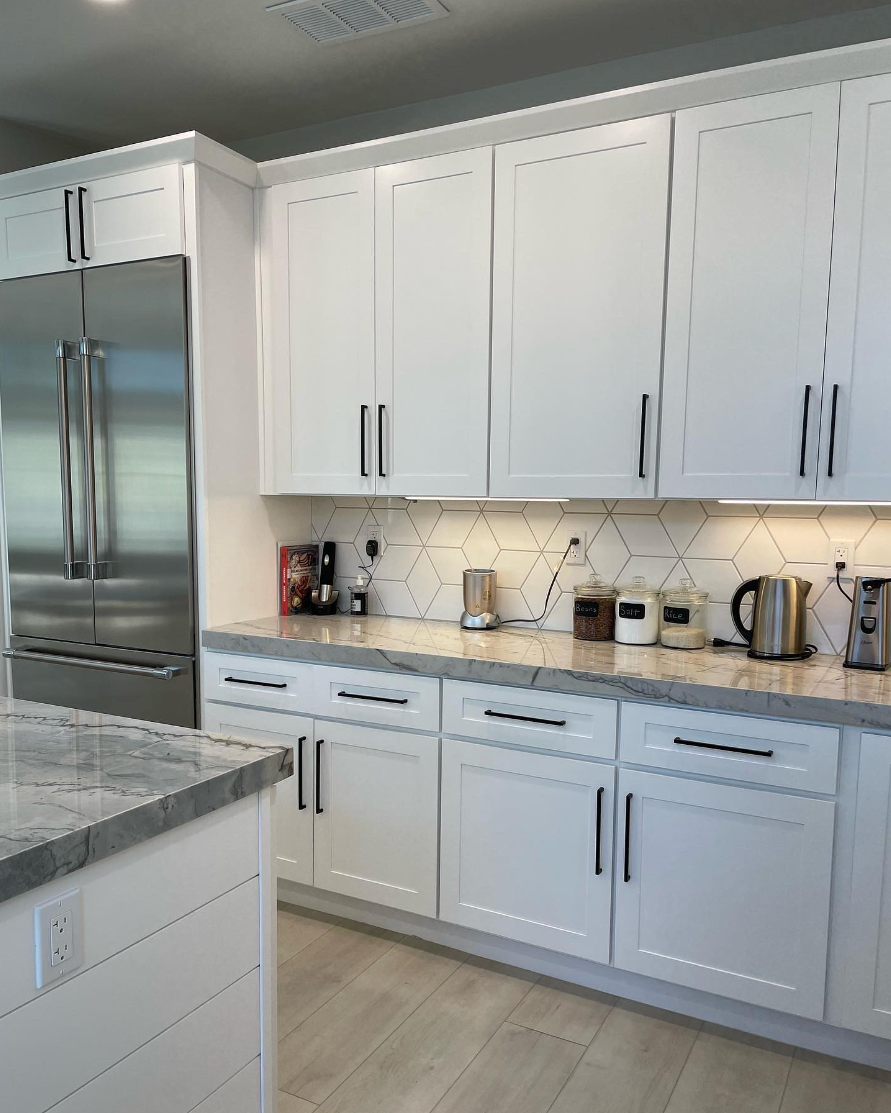 A kitchen with white cabinets and stainless steel appliances