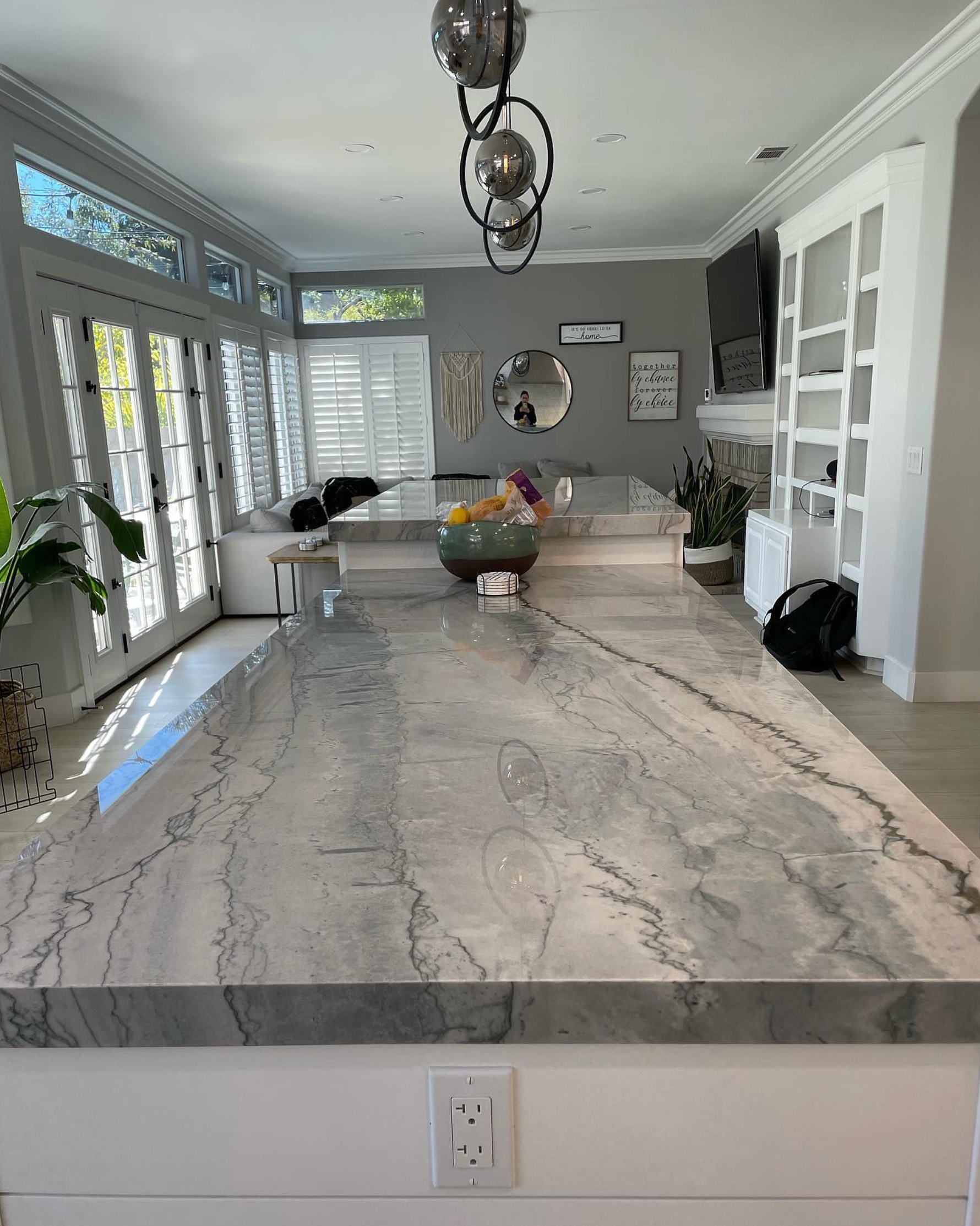 A kitchen with a large granite counter top and a bowl of fruit on it.