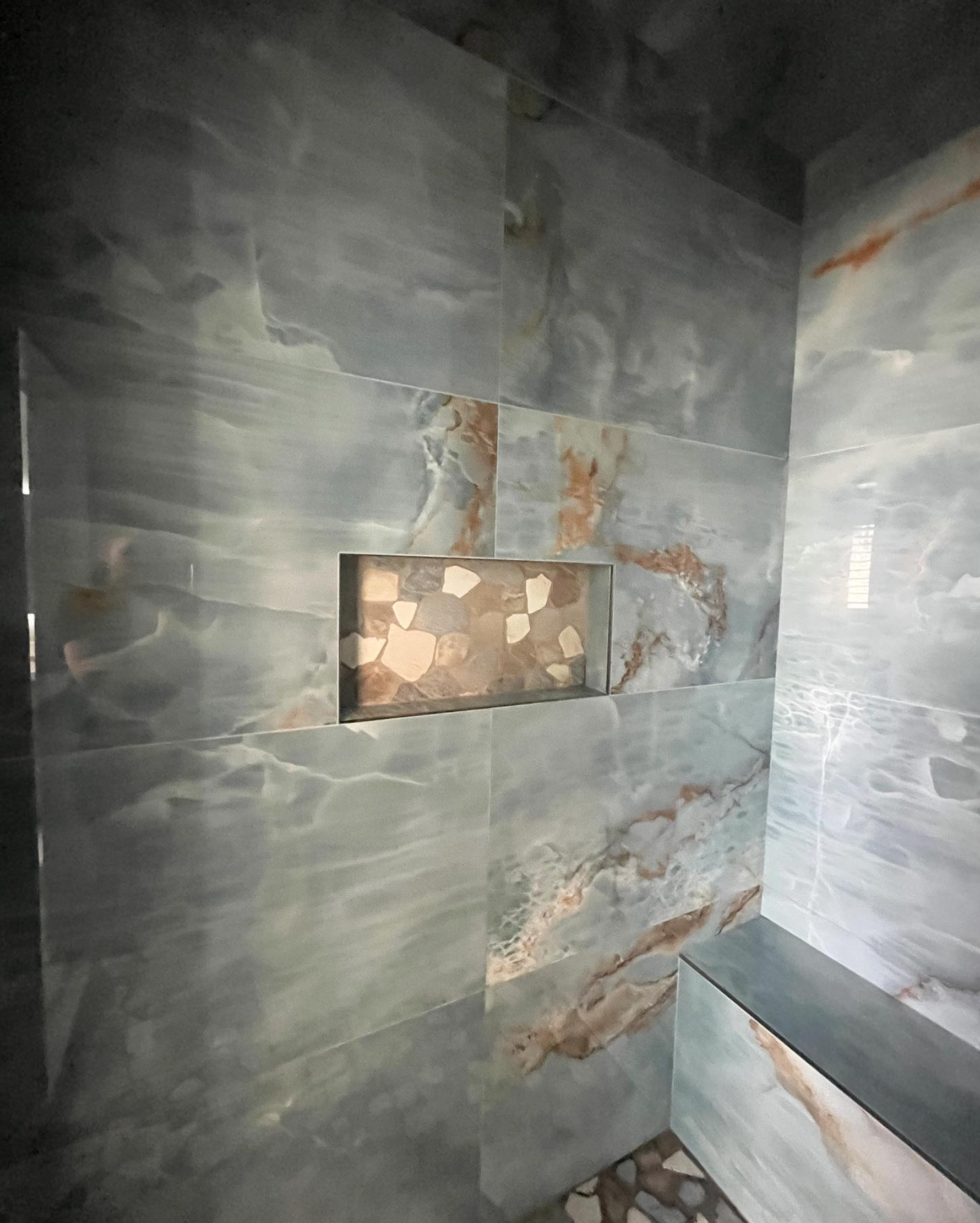 A shower with a niche in the wall and a shelf.