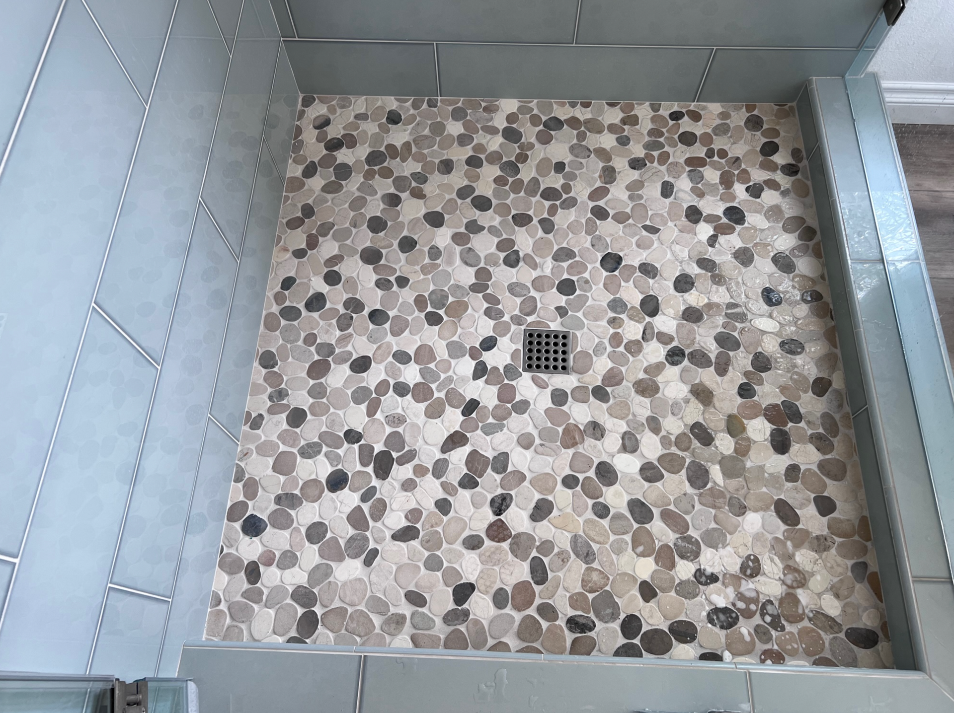 A shower stall with a tiled floor and a drain.
