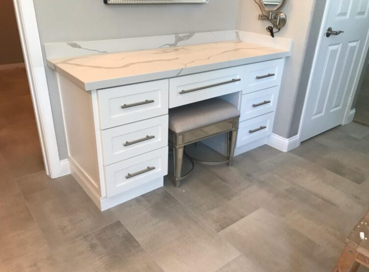 A vanity with drawers and a stool in a bathroom.