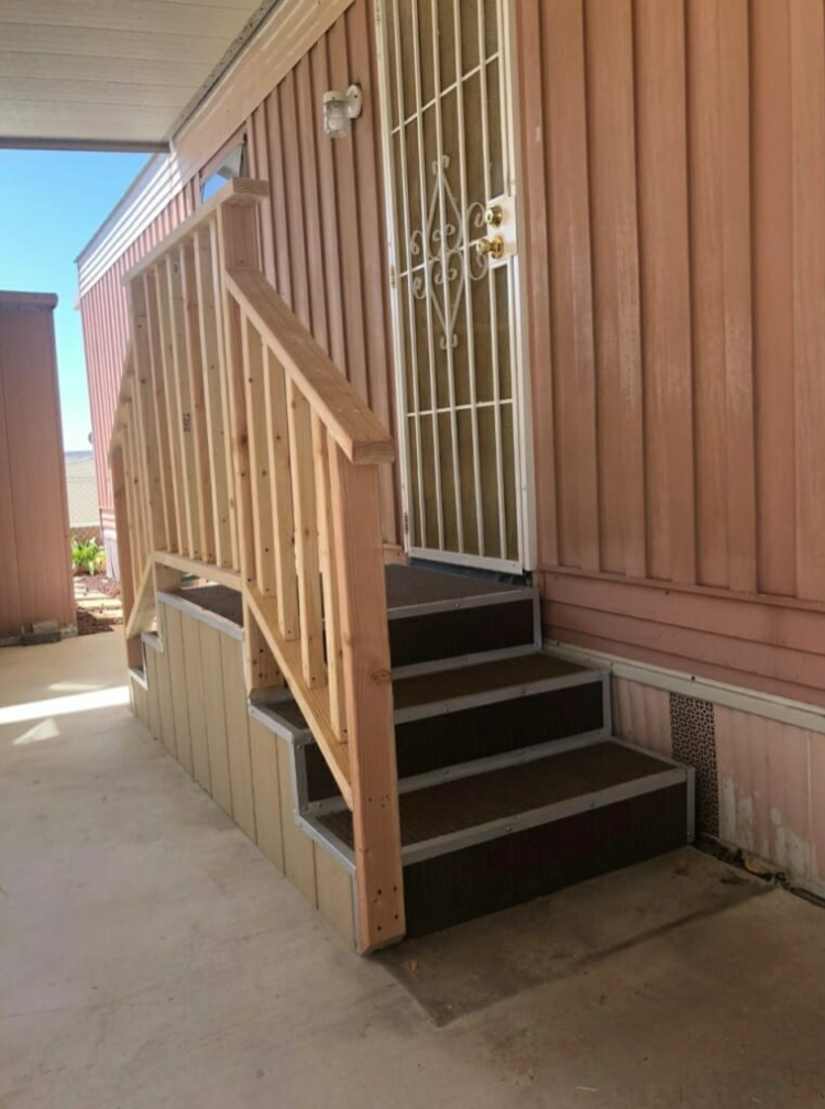 A mobile home with stairs leading up to the front door.
