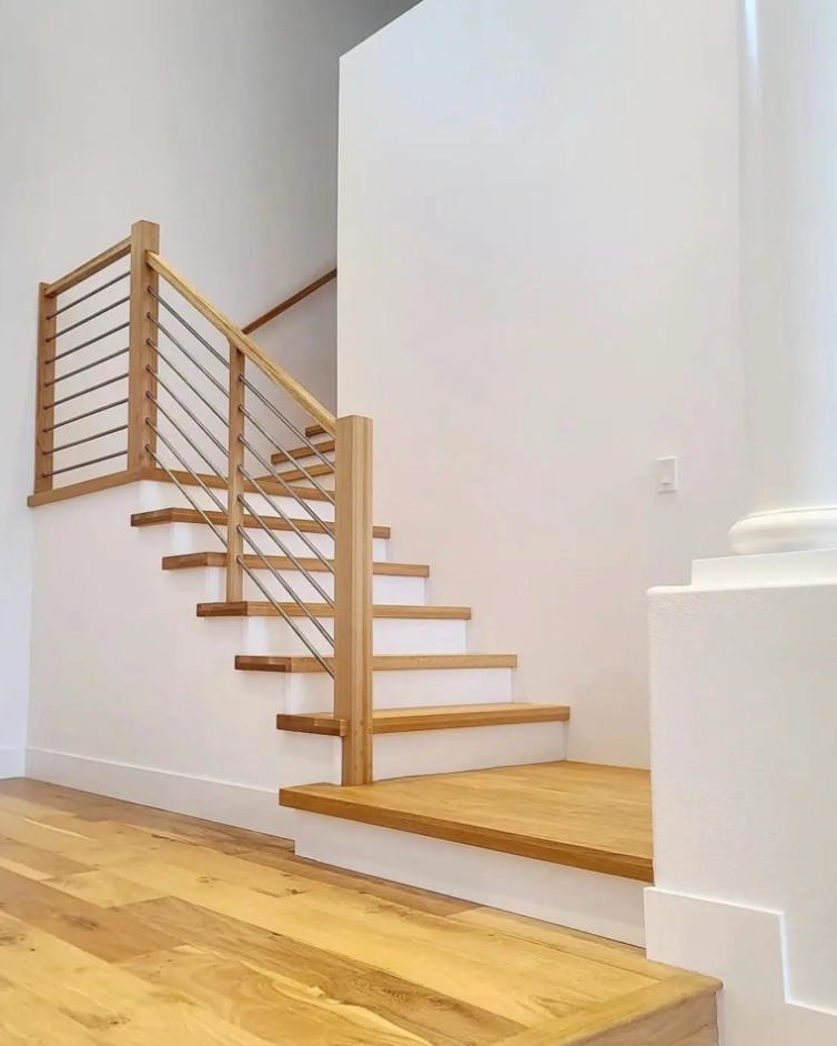 A wooden staircase with a metal railing in a white room