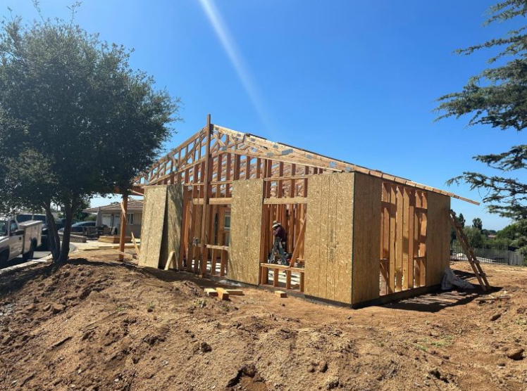 A house is being built in the middle of a dirt field.