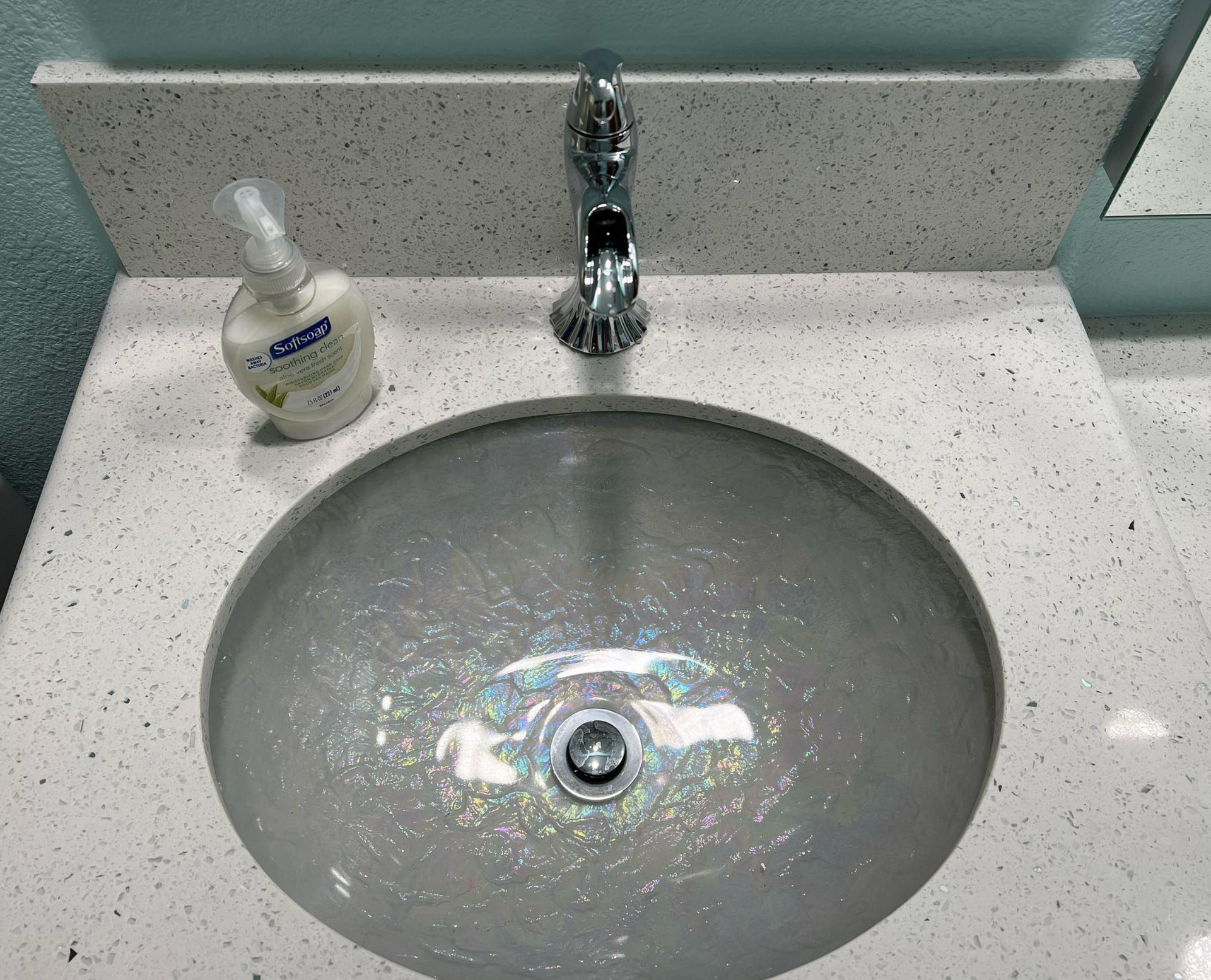A bathroom sink with a soap dispenser next to it