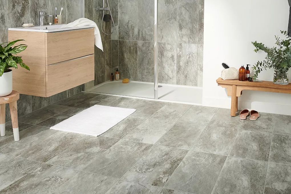 A bathroom with a walk in shower , sink , and bench.