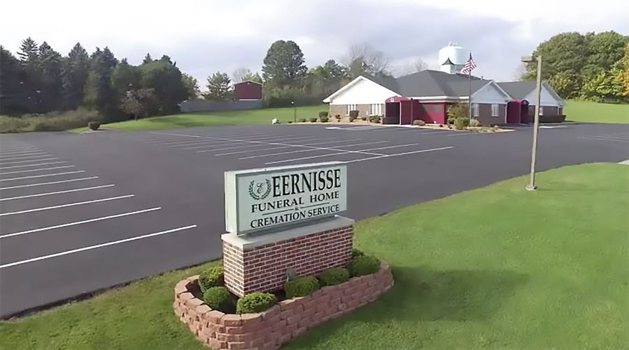 Sign for Eernisse Funeral Home and Cremation Service in front of the building with a large parking lot and green lawn.