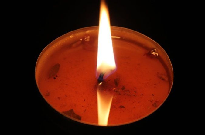 Single candle with flame in dim setting, symbolizing remembrance and reflection in Belgium, WI.
