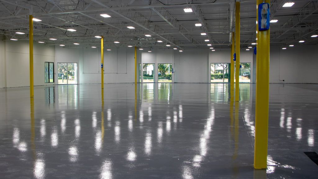 A large empty warehouse with yellow poles and a shiny floor.