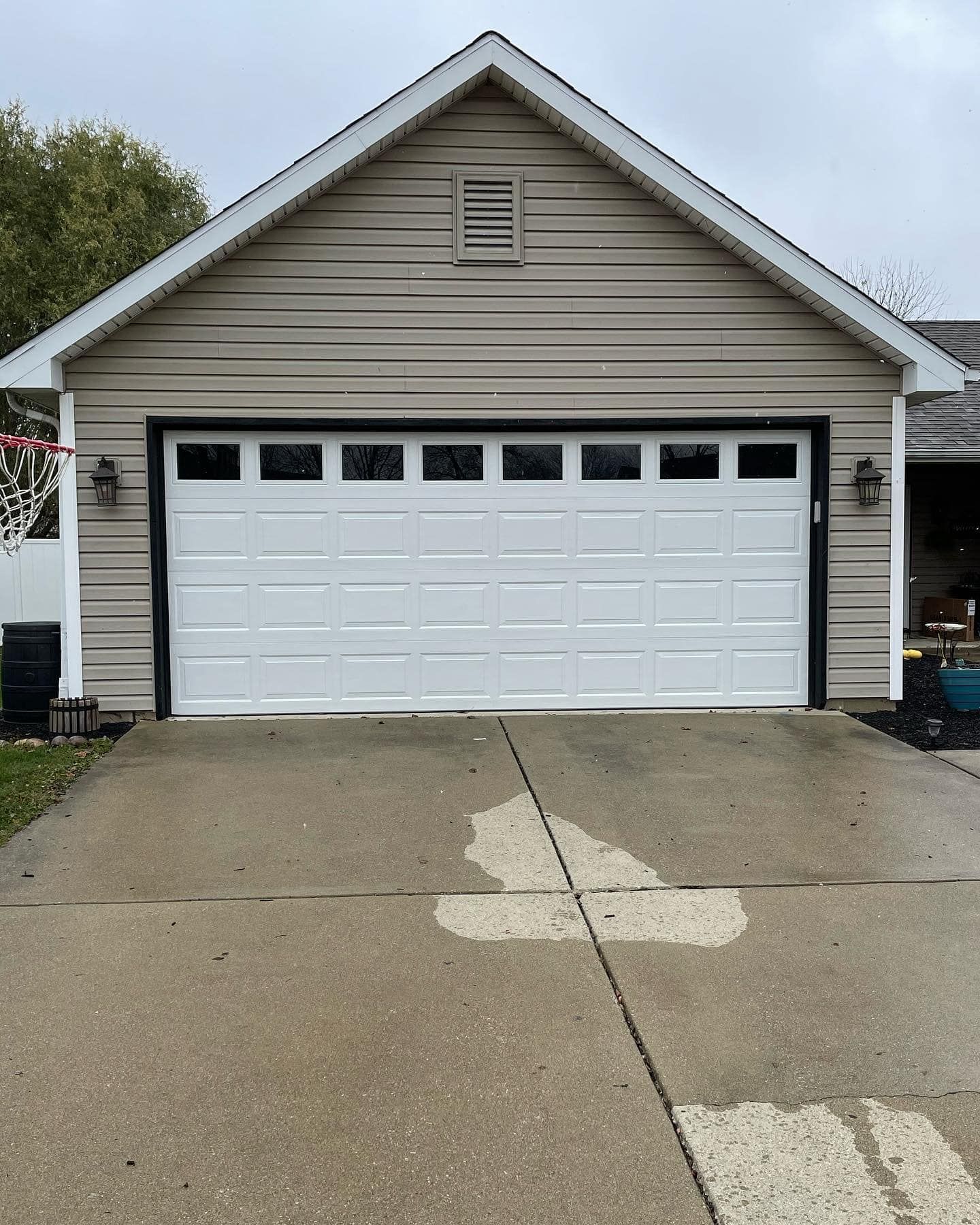 White garage door on a beige building with a concrete driveway on a cloudy day.