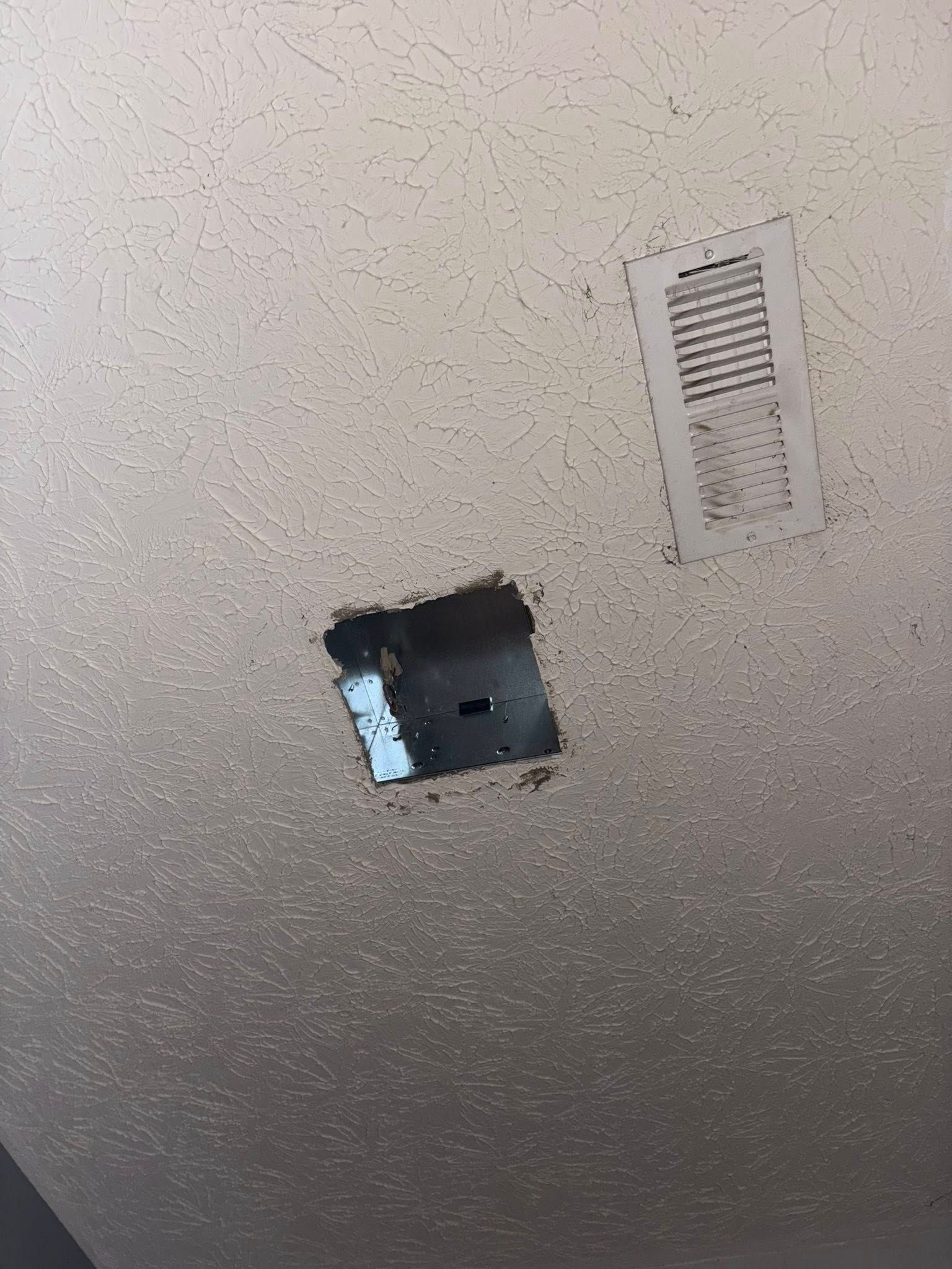 A ceiling with two openings: a rectangular vent and a square access panel.