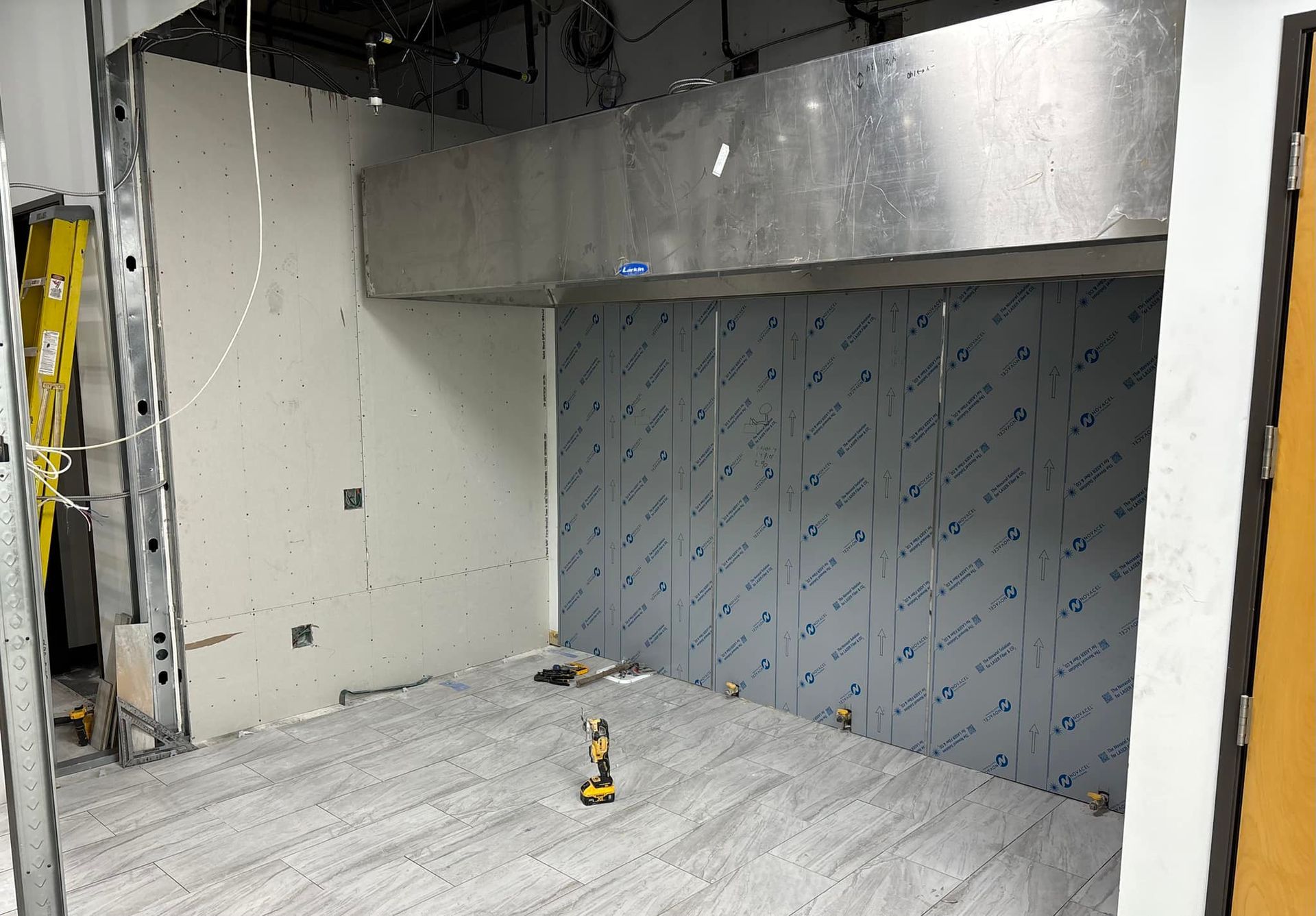 Construction site: a room with unfinished walls, metal ventilation hood, and a textured floor.