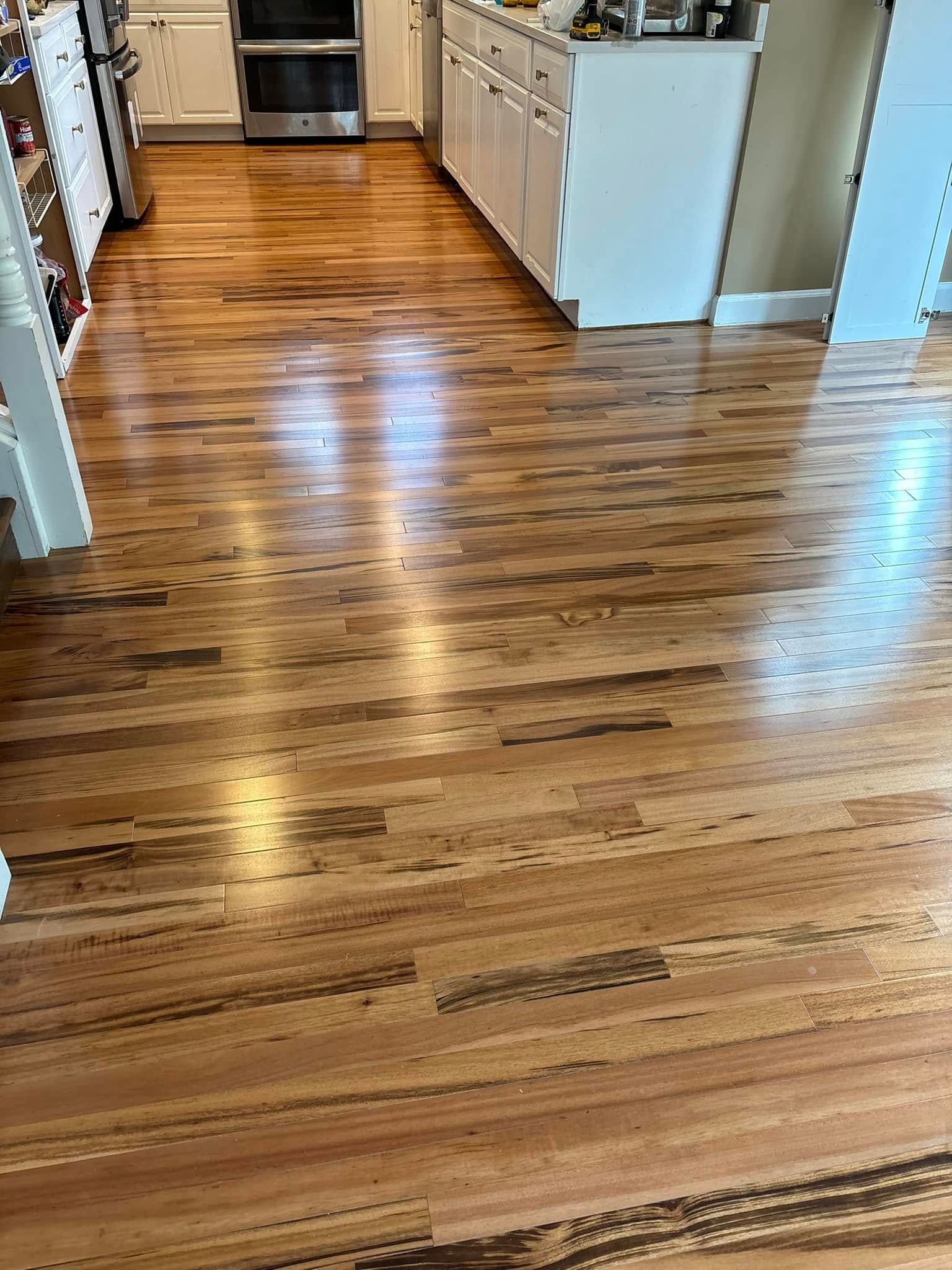 Hardwood floor in a kitchen with wood cabinets and stainless steel appliances.