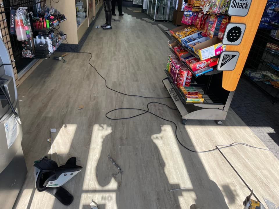Store interior: floor strewn with debris, power cord, display stand, person standing.