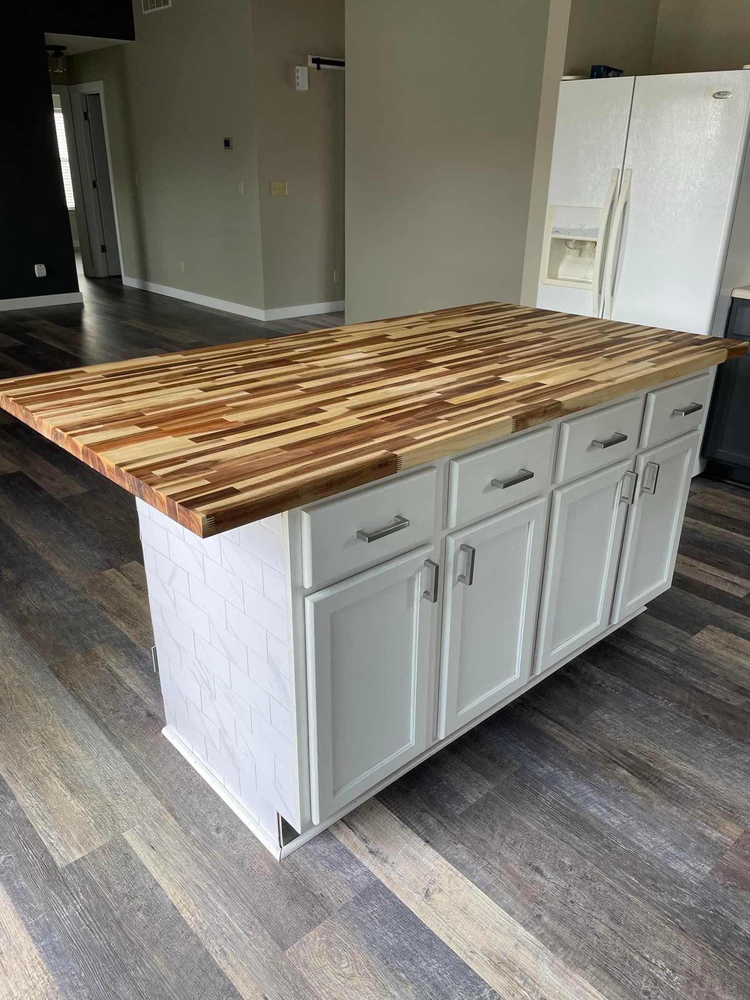 White kitchen island with a wood butcher block countertop.