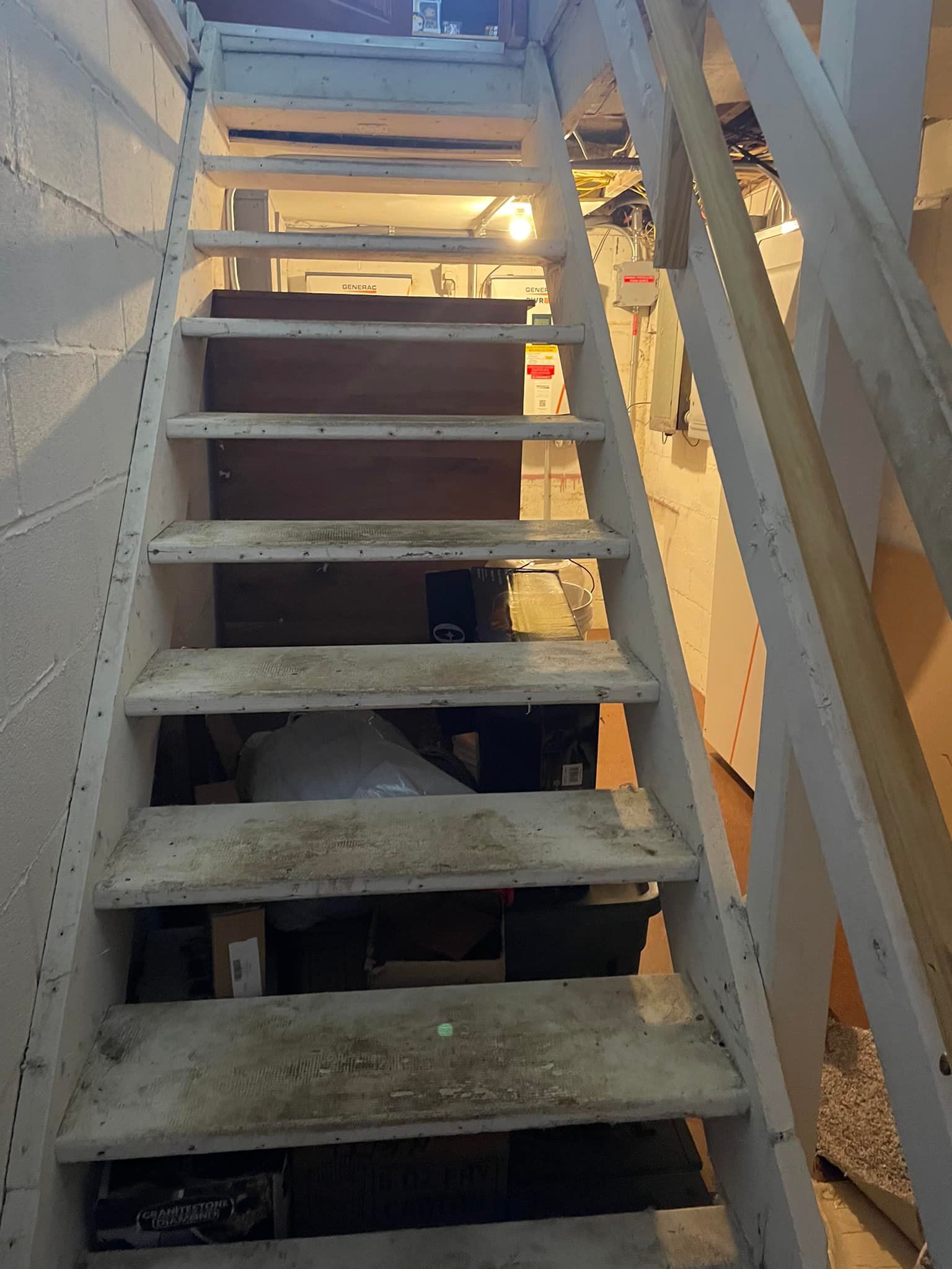 Staircase leading downwards, white stairs and railings. The basement is visible below.