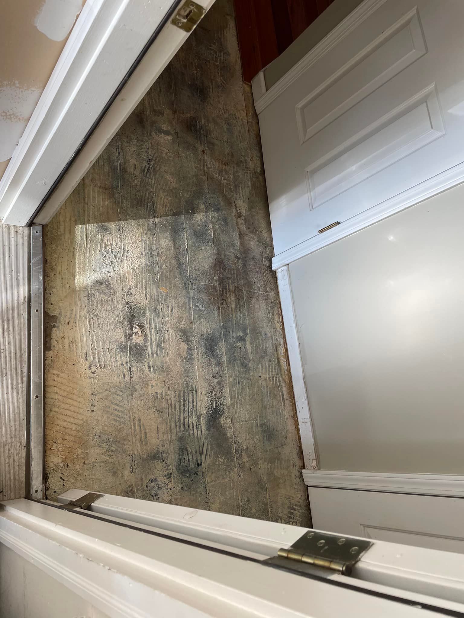A doorway shows a patterned floor in a room, framed by white trim.