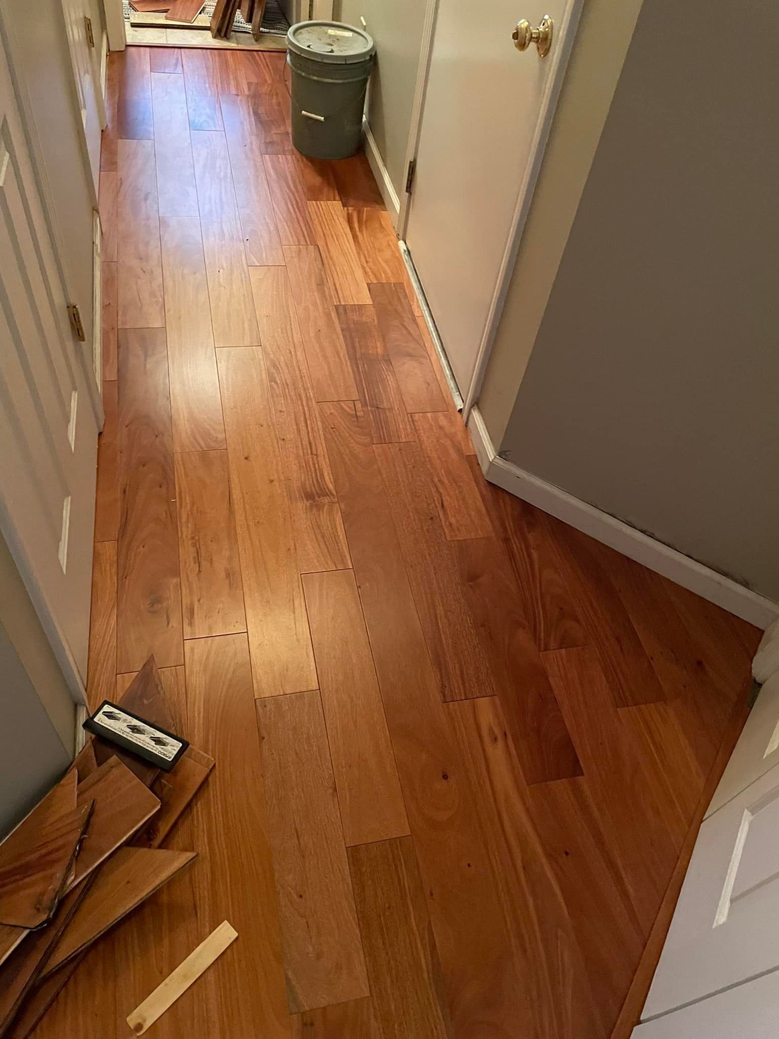 Wooden hallway floor with partial planks and door.