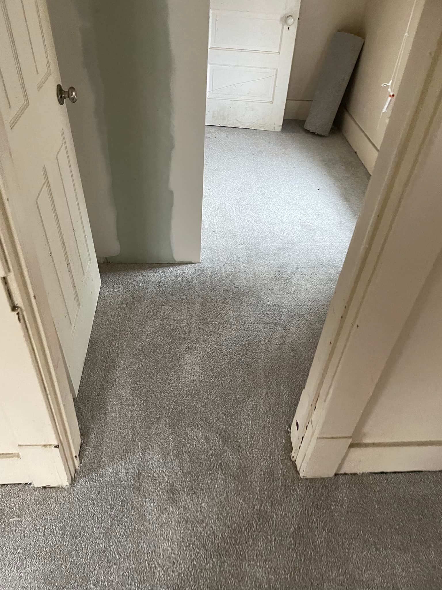 A room with new speckled gray flooring, framed by off-white door frames and doors.