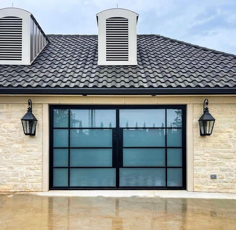 Garage with black framed glass doors, stone exterior, lanterns, and tiled roof.