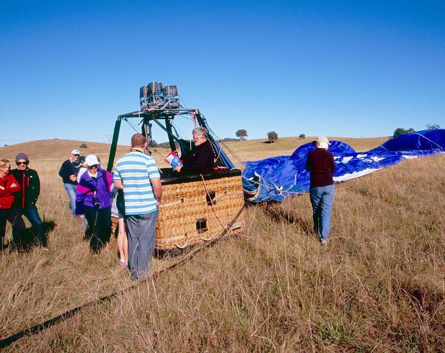 A group of people standing around a hot air balloon in a field