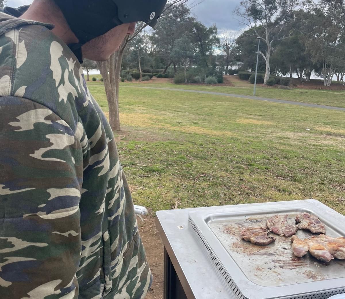 A man in a camouflage shirt is looking at a tray of food. SIL – Supported Independent Living, NDIS, Canberra.